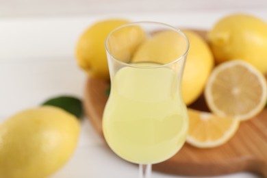 Photo of Liqueur glass with tasty limoncello against blurred background, closeup