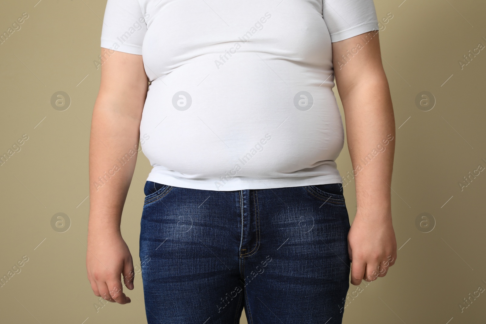 Photo of Overweight man in tight t-shirt on beige background, closeup