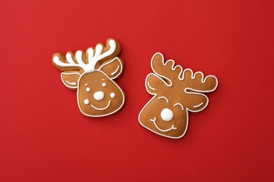 Photo of Christmas deer shaped gingerbread cookies on red background, flat lay