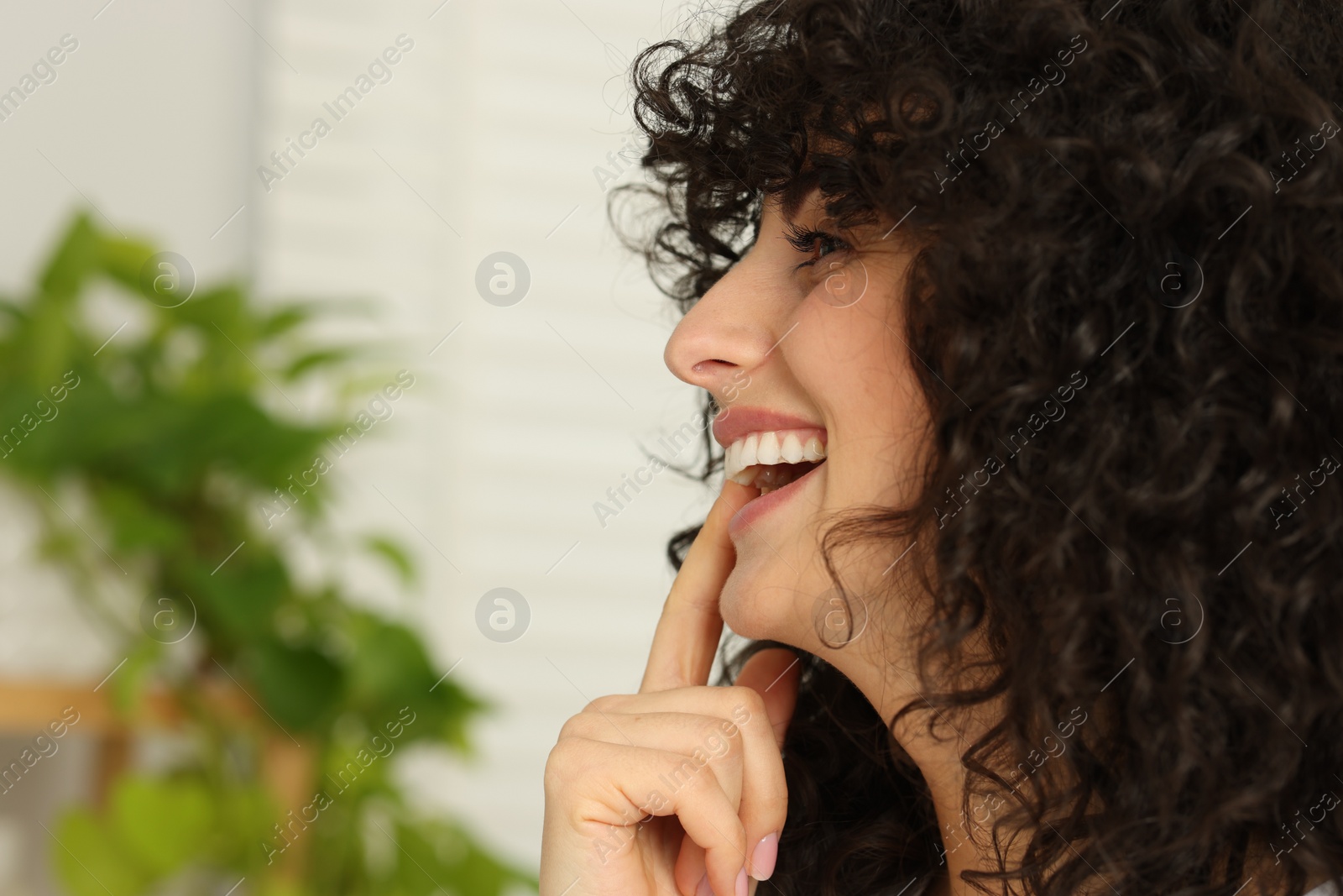 Photo of Young woman applying whitening strip on her teeth indoors, space for text