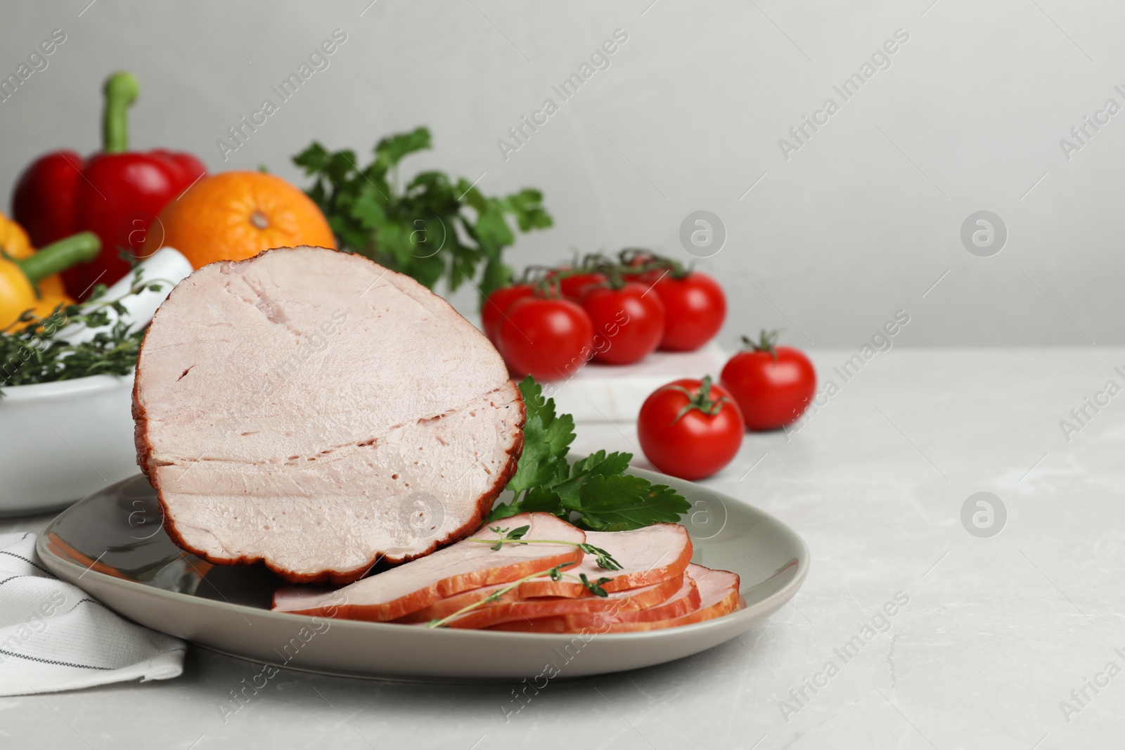 Photo of Delicious cut ham served with parsley on light grey table, space for text