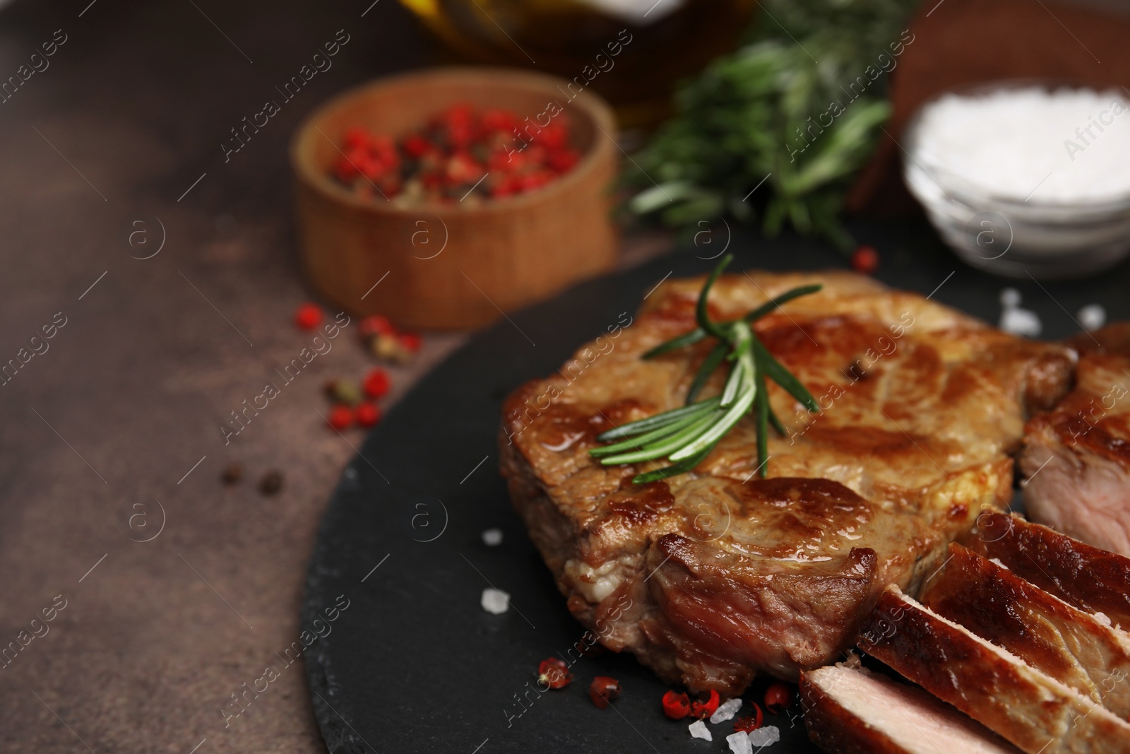 Photo of Delicious fried meat with rosemary and spices on brown table, closeup. Space for text