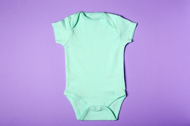 Photo of Cute baby onesie on color background, top view