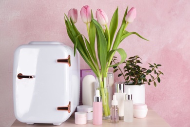 Photo of Cosmetics refrigerator and skin care products on table