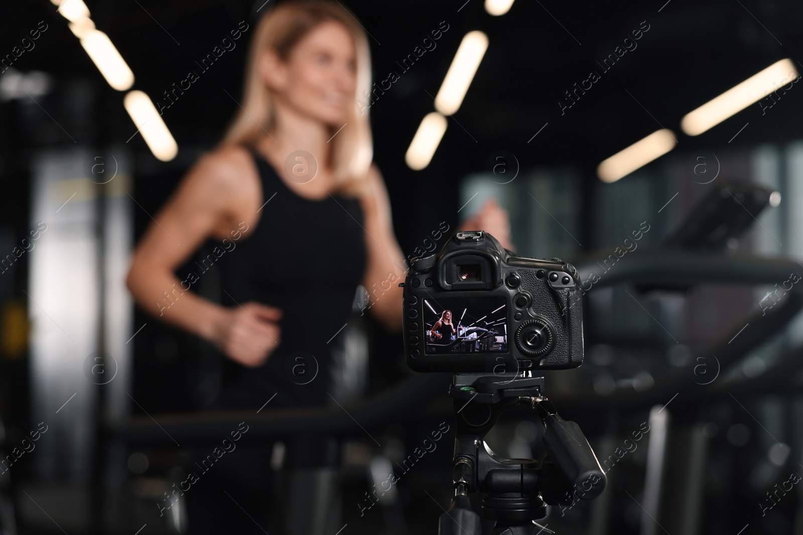 Photo of Fitness trainer recording online classes in gym, focus on camera. Space for text