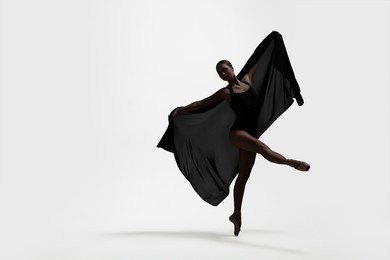 Image of Beautiful ballerina with black veil dancing on light background, space for text. Dark silhouette of dancer