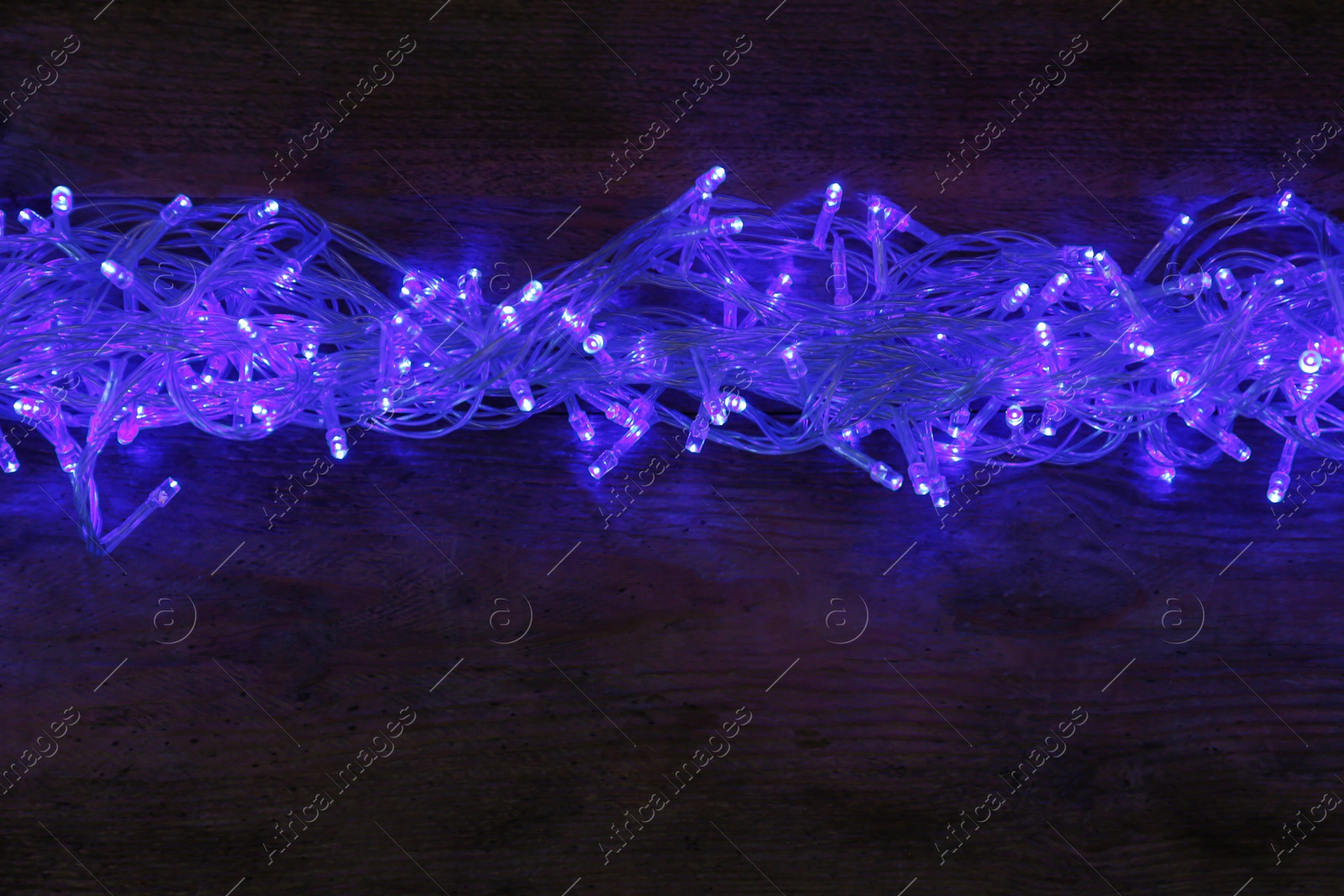 Photo of Blue Christmas lights on wooden background, top view. Space for text