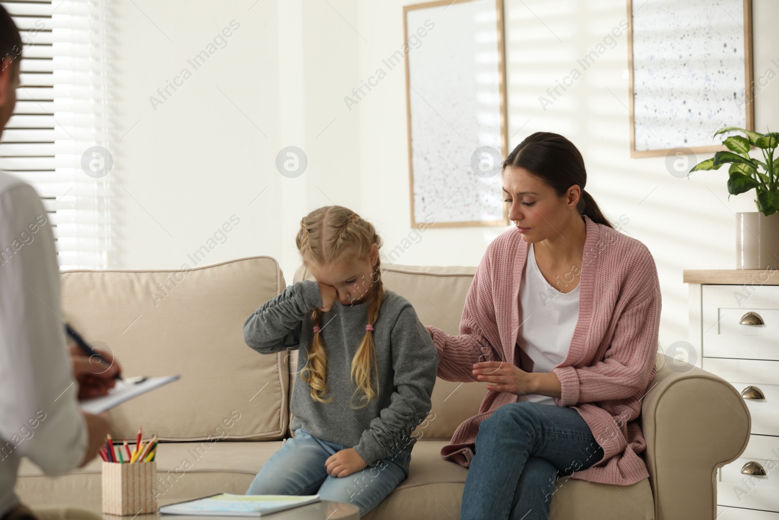 Photo of Little girl and her mother on appointment with child psychotherapist indoors