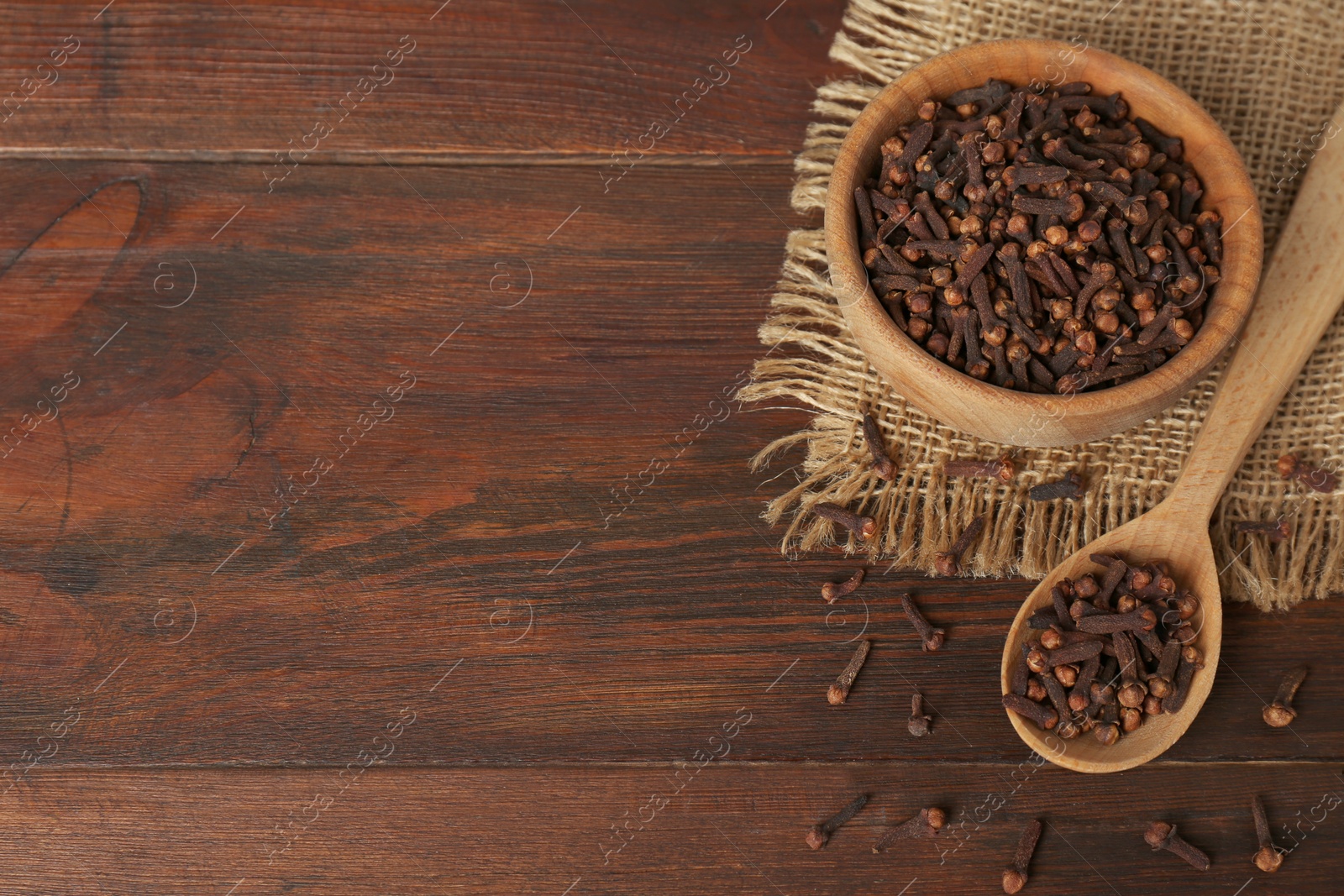 Photo of Aromatic dry cloves on wooden table, above view. Space for text