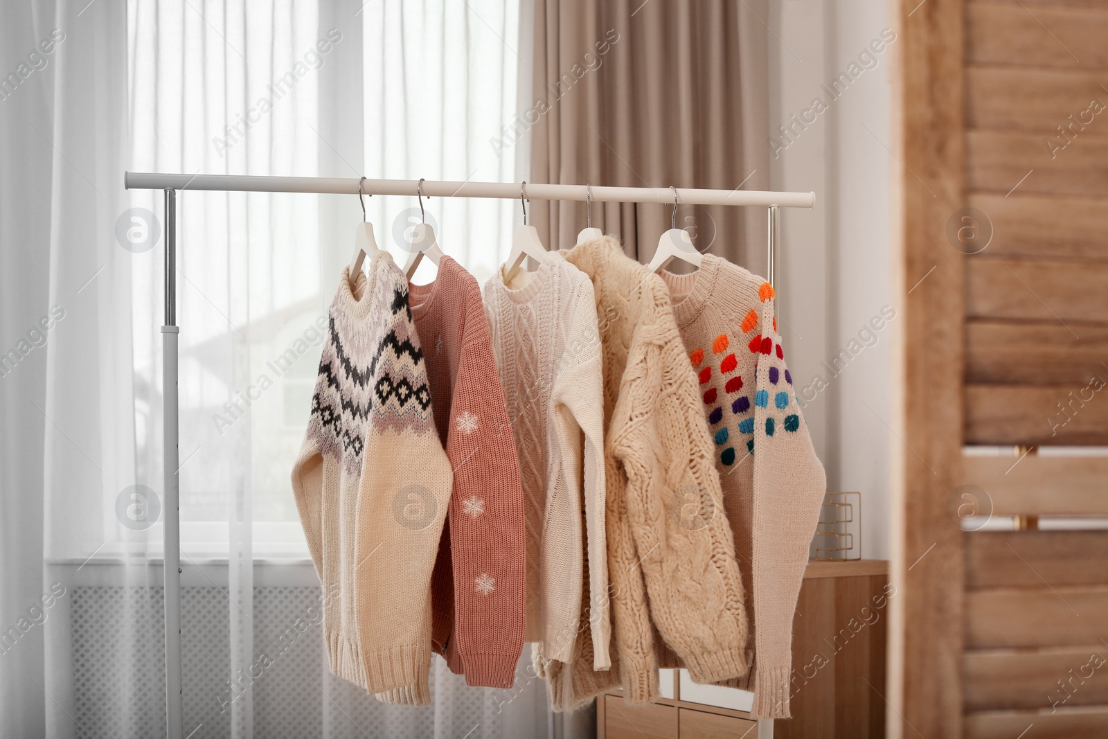 Photo of Wardrobe rack with stylish warm clothes indoors