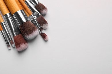 Photo of Set of makeup brushes on white background, above view. Space for text