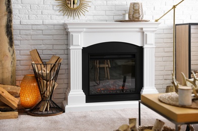 Photo of Firewood in holder near modern fireplace in living room