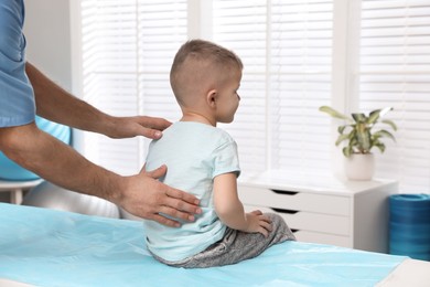 Photo of Orthopedist examining child's back in clinic, closeup. Scoliosis treatment
