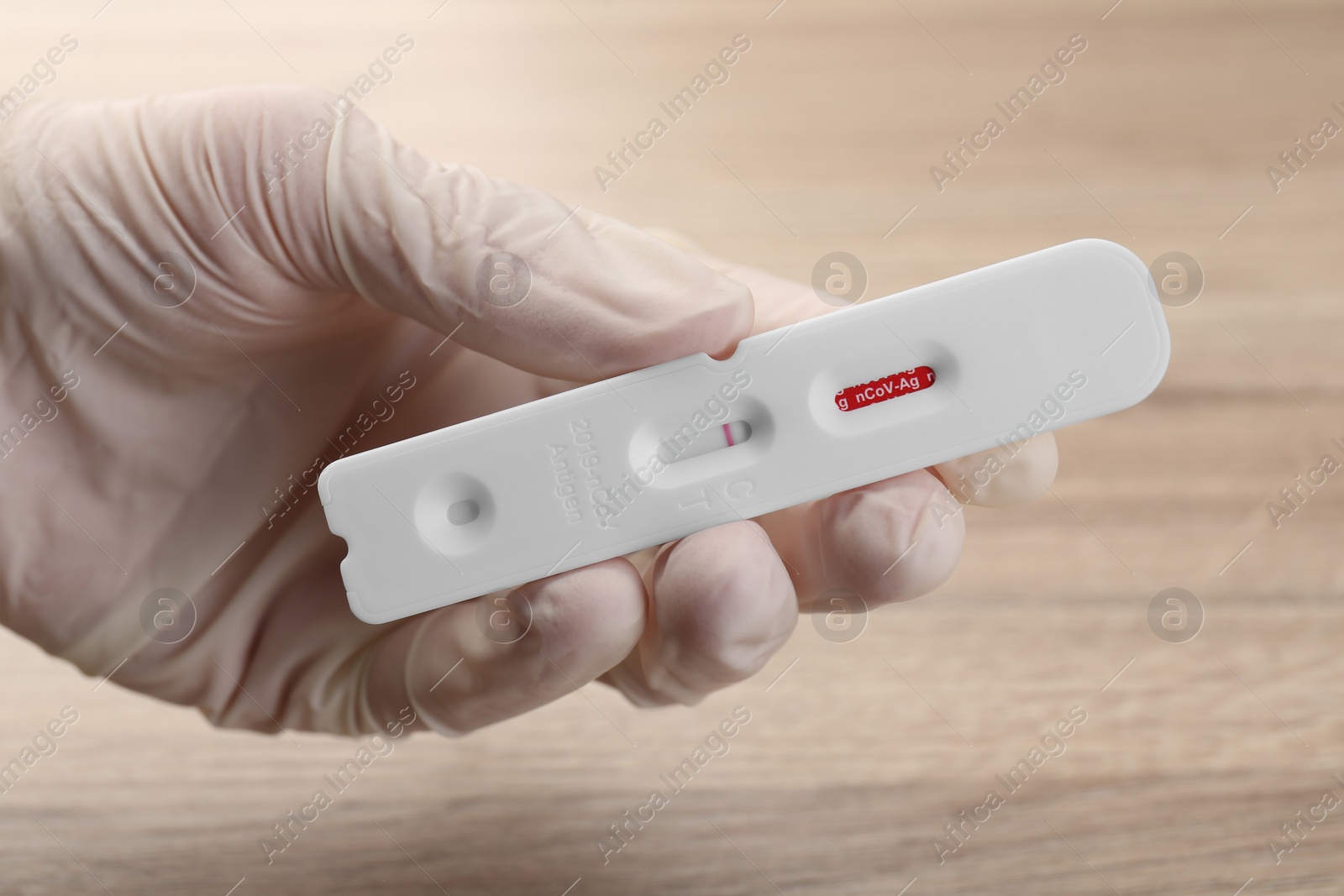 Photo of Doctor holding disposable Covid-19 express test at wooden table, closeup