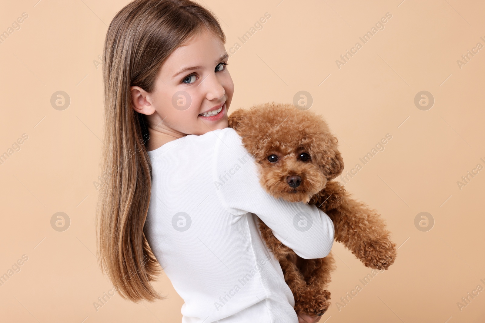 Photo of Little child with cute puppy on beige background. Lovely pet