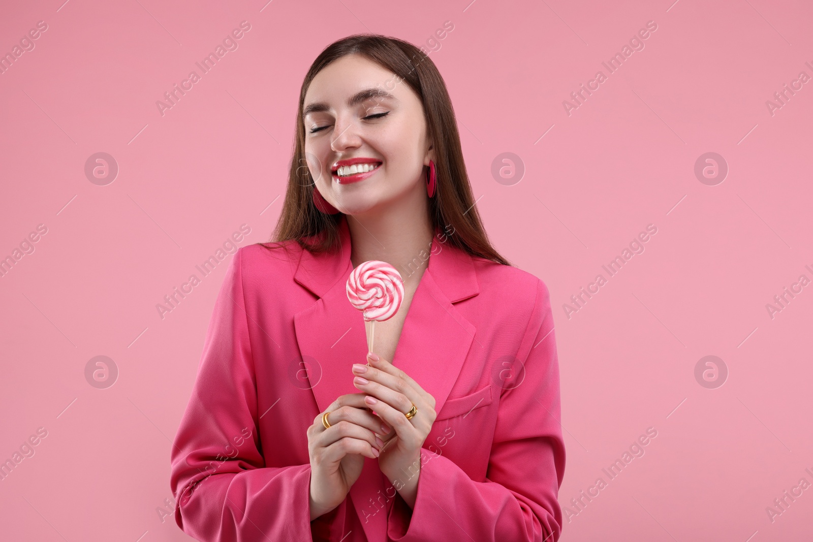 Photo of Pink look. Beautiful woman with lollipop on color background