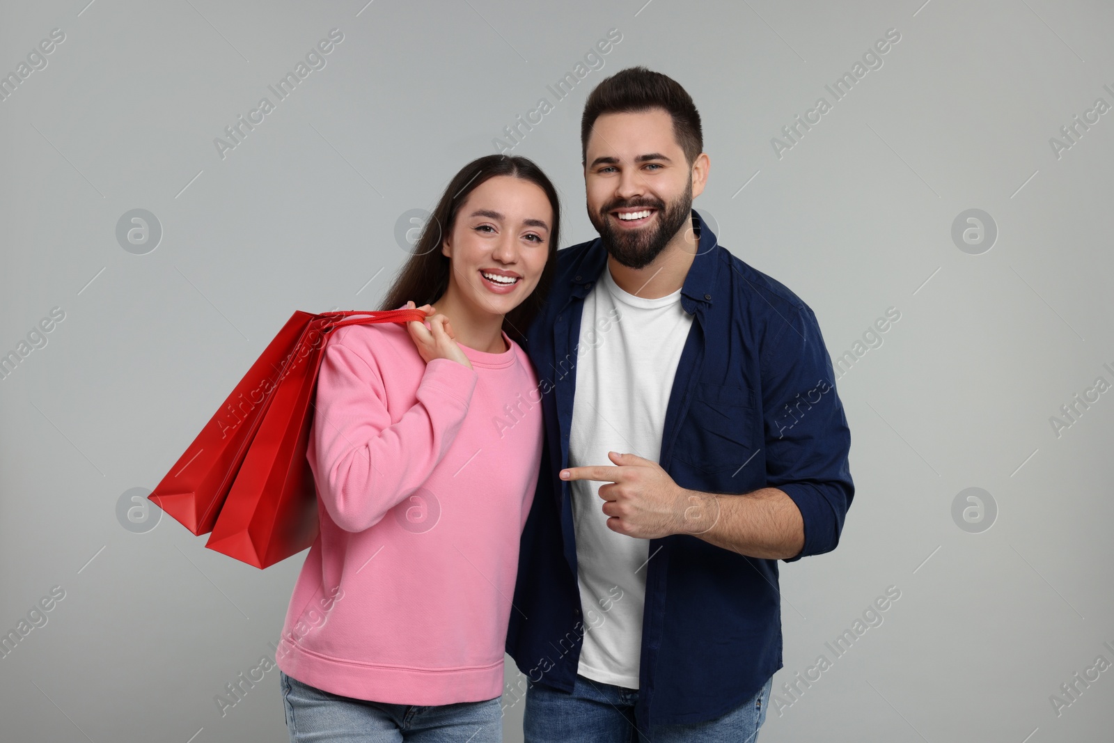 Photo of Happy couple with shopping bags on grey background