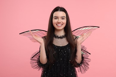 Photo of Beautiful girl in fairy costume with wings on pink background