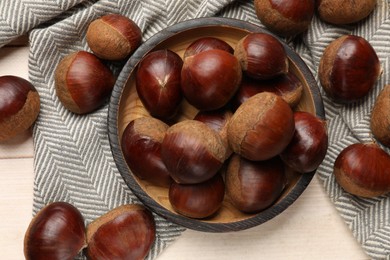 Sweet fresh edible chestnuts on light wooden table, top view