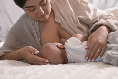 Photo of Mother breastfeeding her newborn baby on bed, closeup