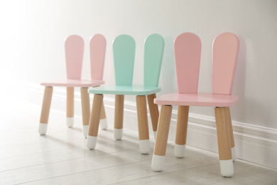 Cute little chairs with bunny ears near white wall indoors. Children's room interior