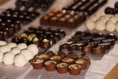 Photo of Many delicious chocolate candies on table, closeup. Production line