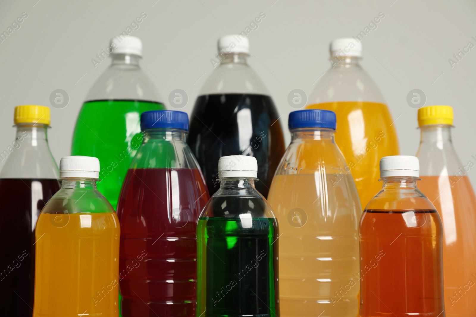 Photo of Bottles of soft drinks on grey background, closeup