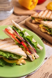 Photo of Green plate with tasty sandwiches on wooden table, closeup. Space for text