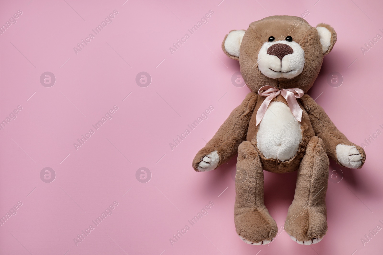 Photo of Cute teddy bear on pink background, top view. Space for text