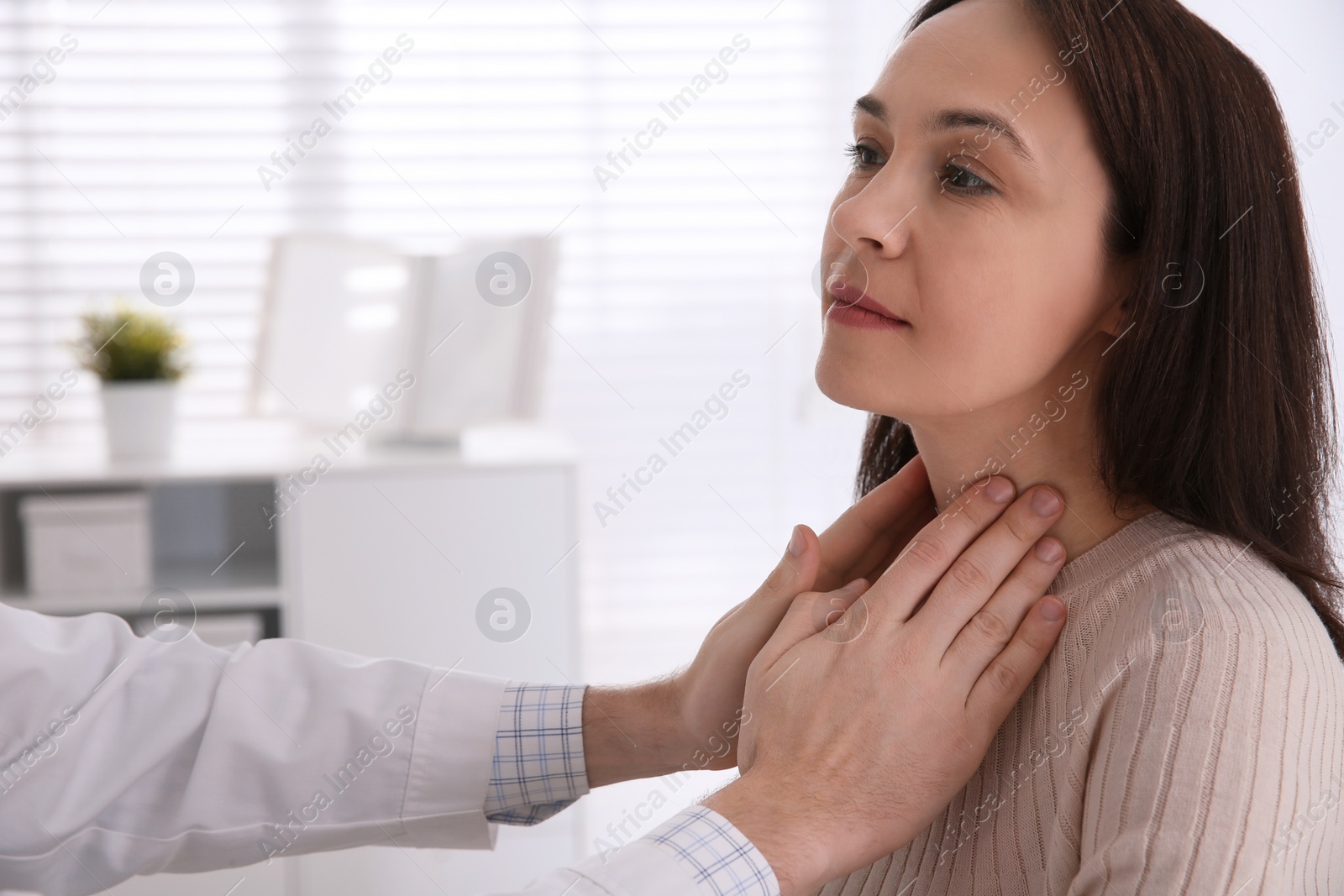 Photo of Doctor examining thyroid gland of patient in hospital, closeup. Space for text