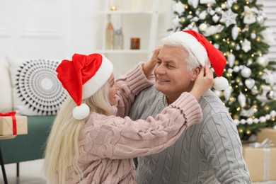 Photo of Happy mature couple in Santa hats at home. Christmas celebration