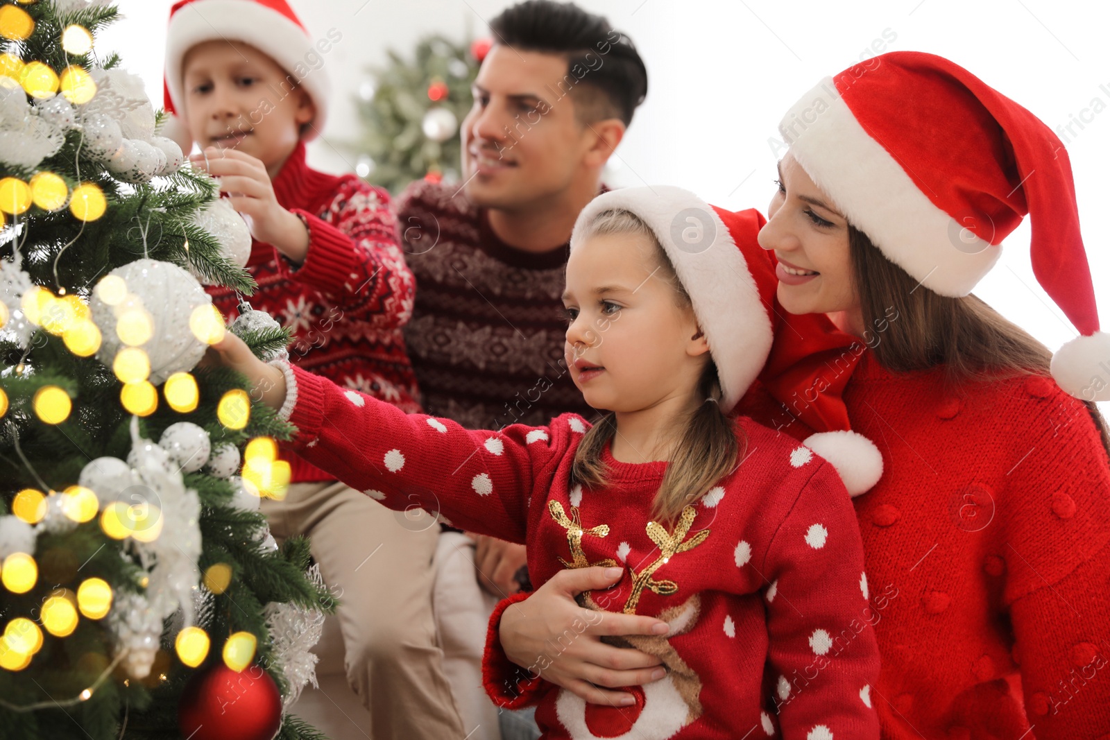 Photo of Happy family with cute children decorating Christmas tree together at home