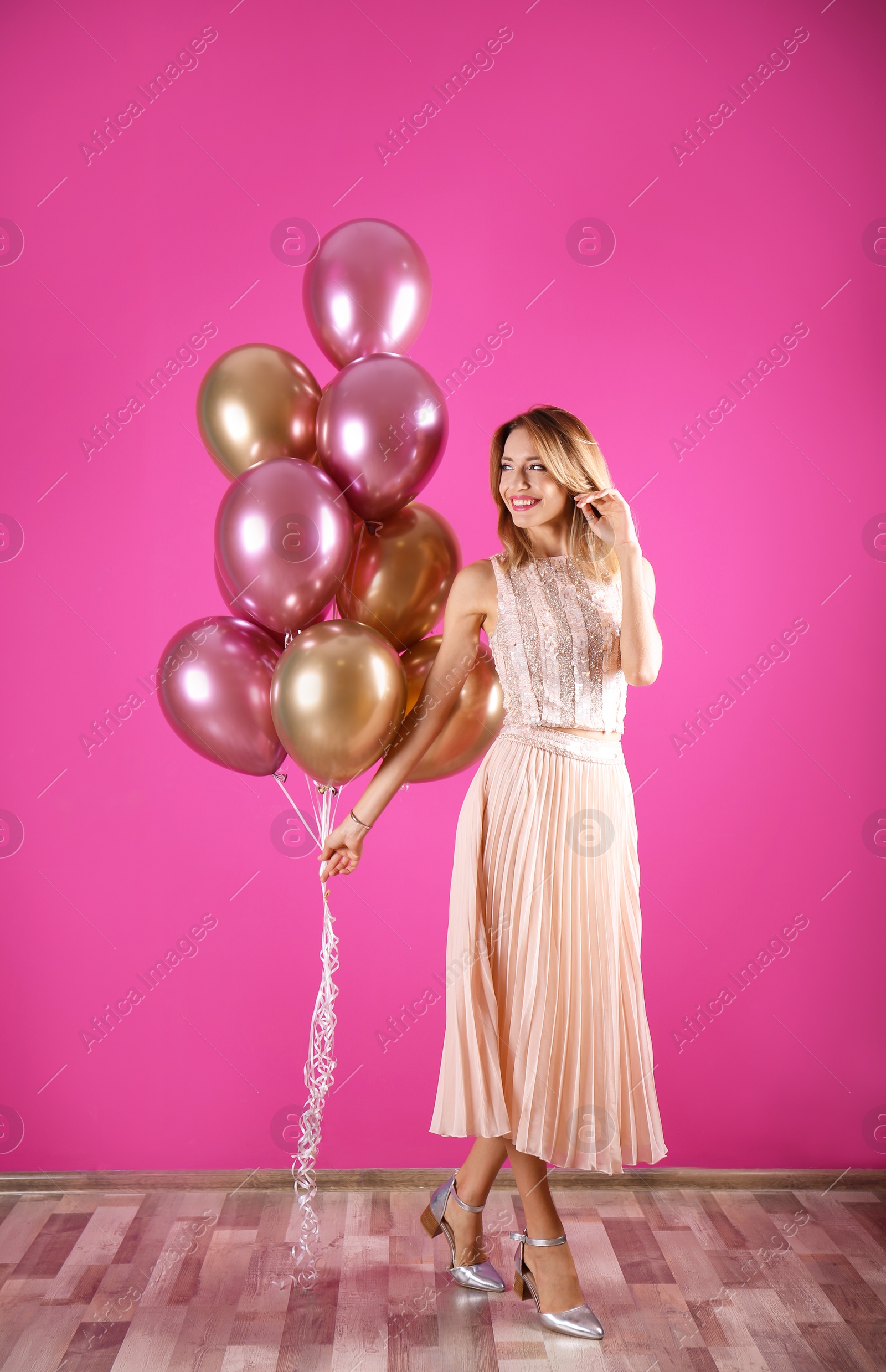 Photo of Young woman with air balloons near color wall