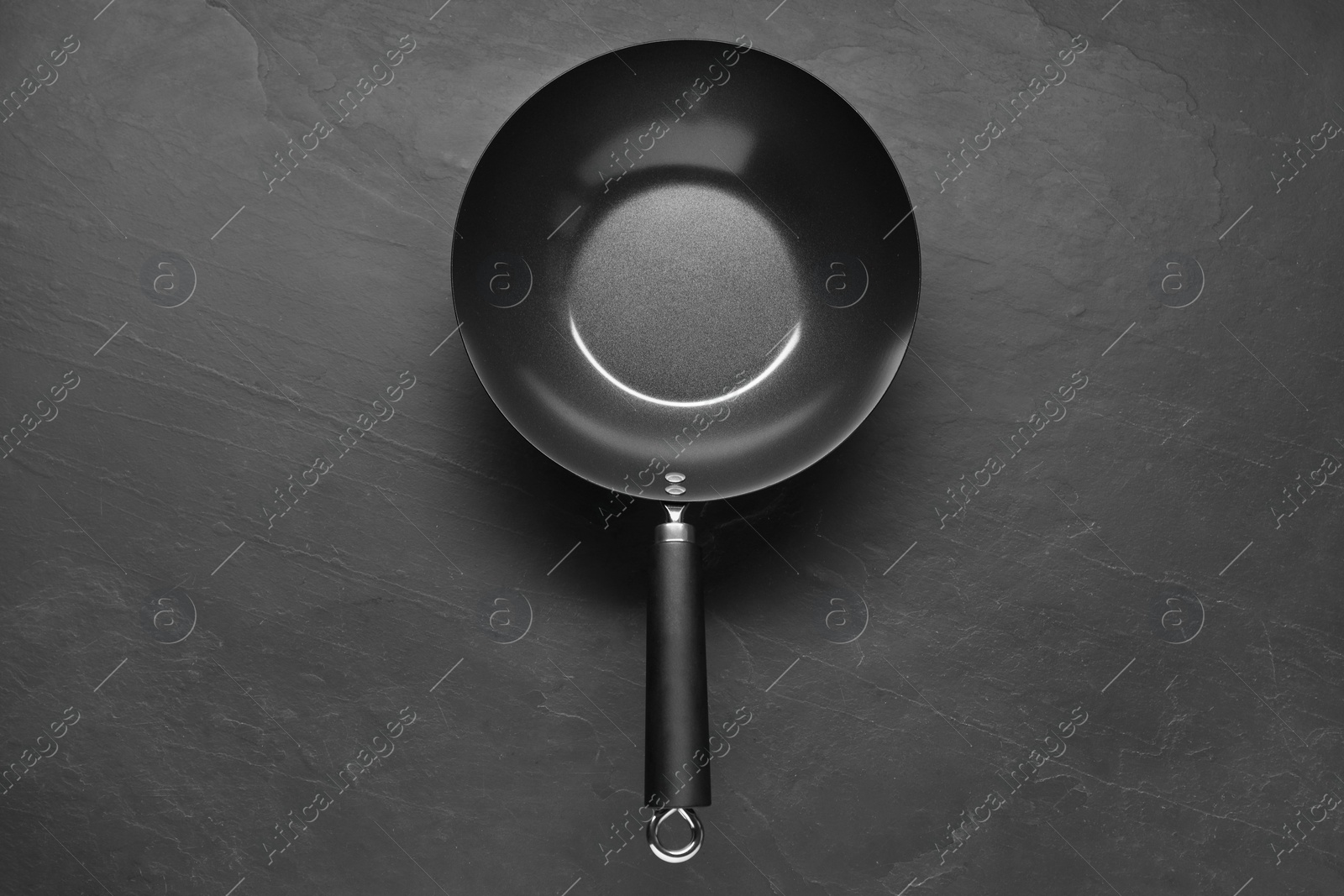 Photo of Empty iron wok on black textured table, top view. Chinese cookware