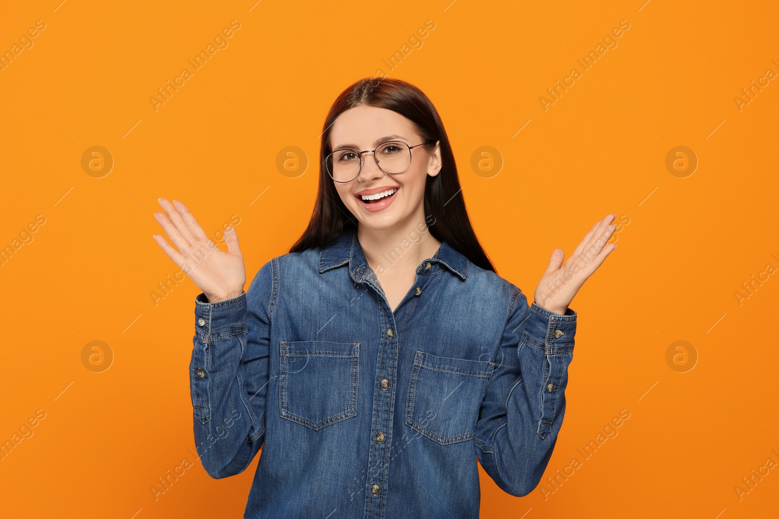 Photo of Portrait of emotional woman in stylish eyeglasses on orange background