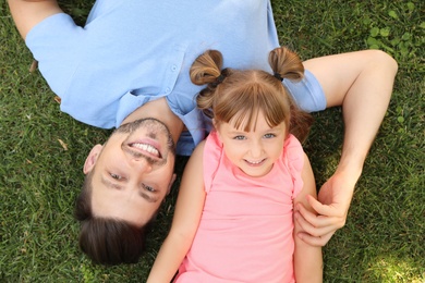 Photo of Father with his cute child on green grass in park, top view. Happy family