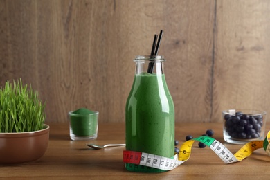Bottle of spirulina smoothie and measuring tape on table