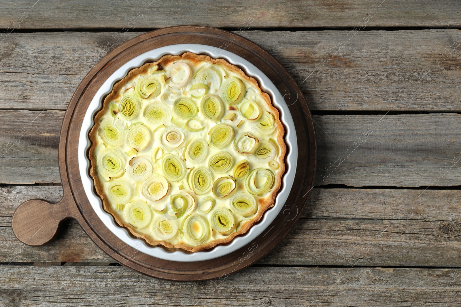 Photo of Freshly baked leek pie on old wooden table, top view. Space for text