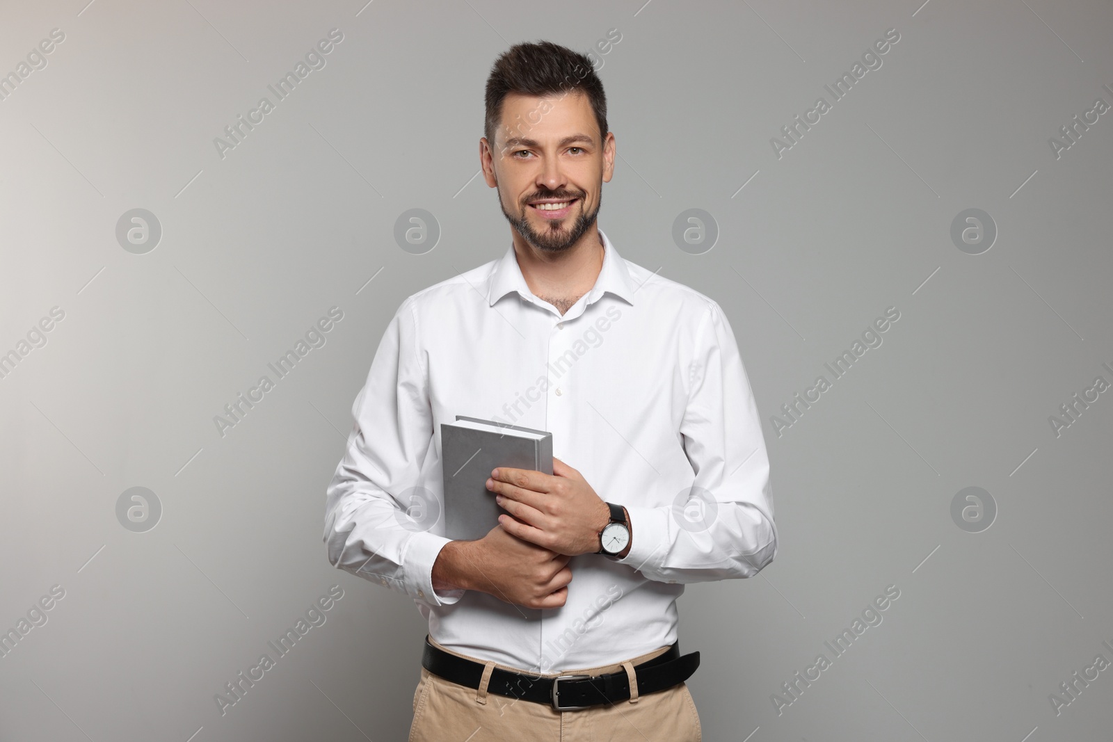 Photo of Happy teacher with book against beige background