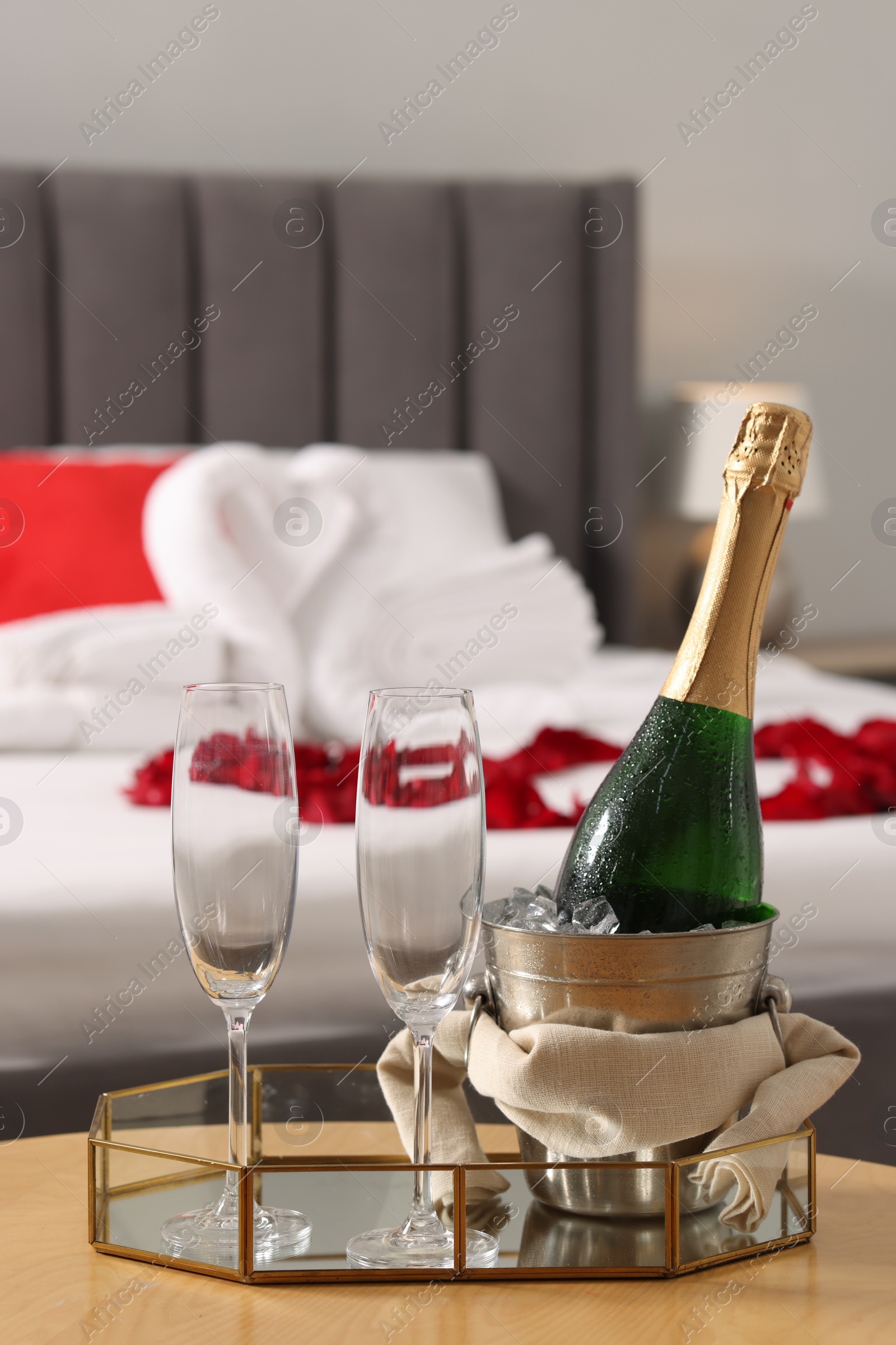 Photo of Honeymoon. Sparkling wine and glasses on wooden table in room