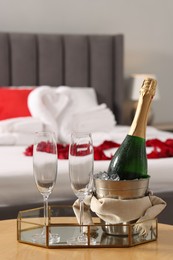 Honeymoon. Sparkling wine and glasses on wooden table in room