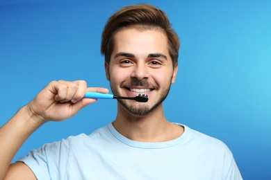 Photo of Portrait of young man with toothbrush on color background