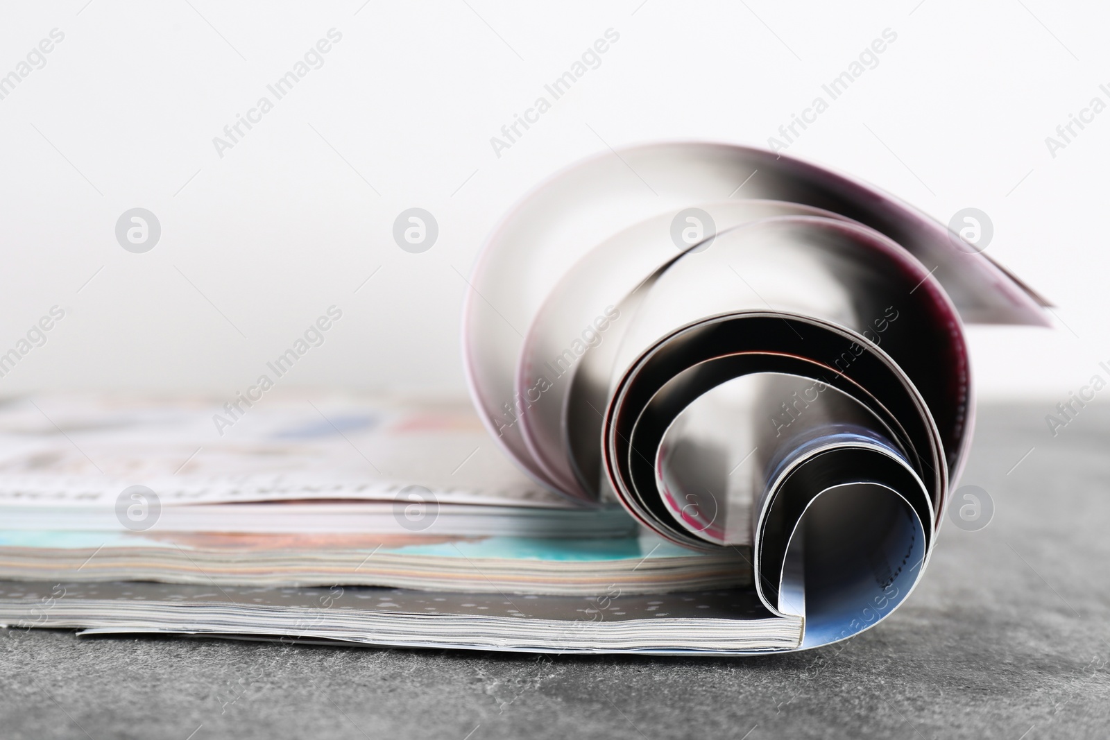 Photo of Three open magazines on grey stone table, closeup