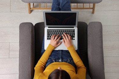 Woman working with laptop in armchair, top view