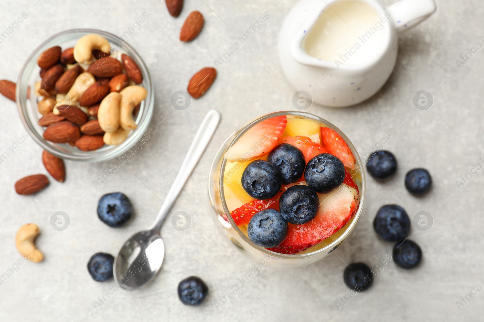Photo of Delicious fruit salad, fresh berries and nuts on light grey table, flat lay