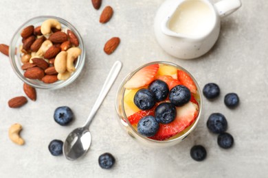 Delicious fruit salad, fresh berries and nuts on light grey table, flat lay