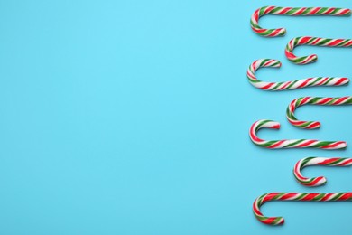 Photo of Many sweet Christmas candy canes on light blue background, flat lay. Space for text