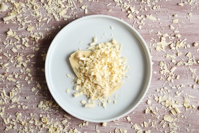 Flat lay composition with plate of white chocolate curls on wooden background