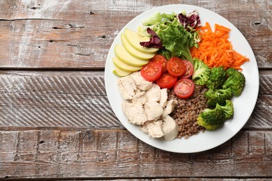 Balanced diet and healthy foods. Plate with different delicious products on wooden table, top view. Space for text