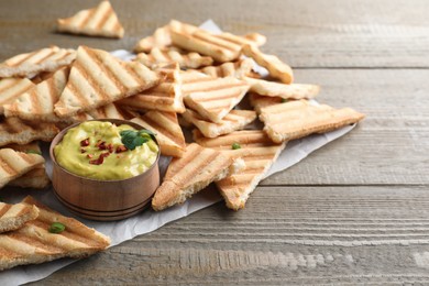 Delicious pita chips and hummus on wooden table